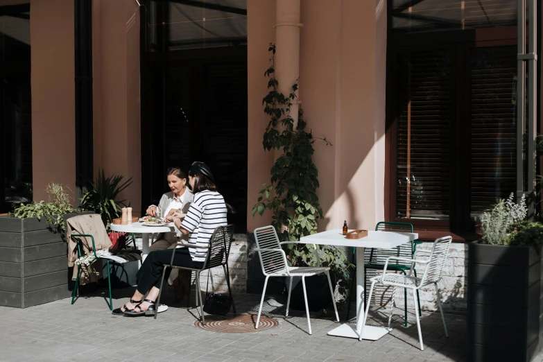 a couple of people that are sitting at a table, trending on unsplash, north melbourne street, well shaded, two women, the flamingo cafe