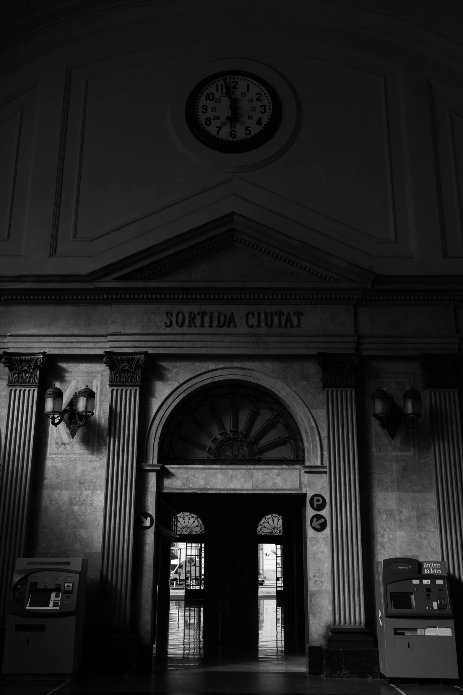 a black and white photo of a building with a clock, a black and white photo, inspired by Thomas Struth, neoclassicism, church interior, doorways, station, dark aesthetic