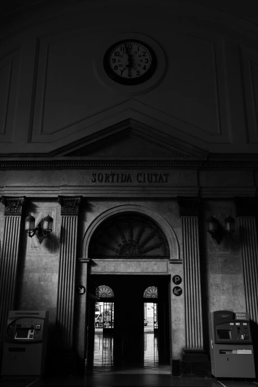 a black and white photo of a building with a clock, a black and white photo, inspired by Thomas Struth, neoclassicism, church interior, doorways, station, dark aesthetic