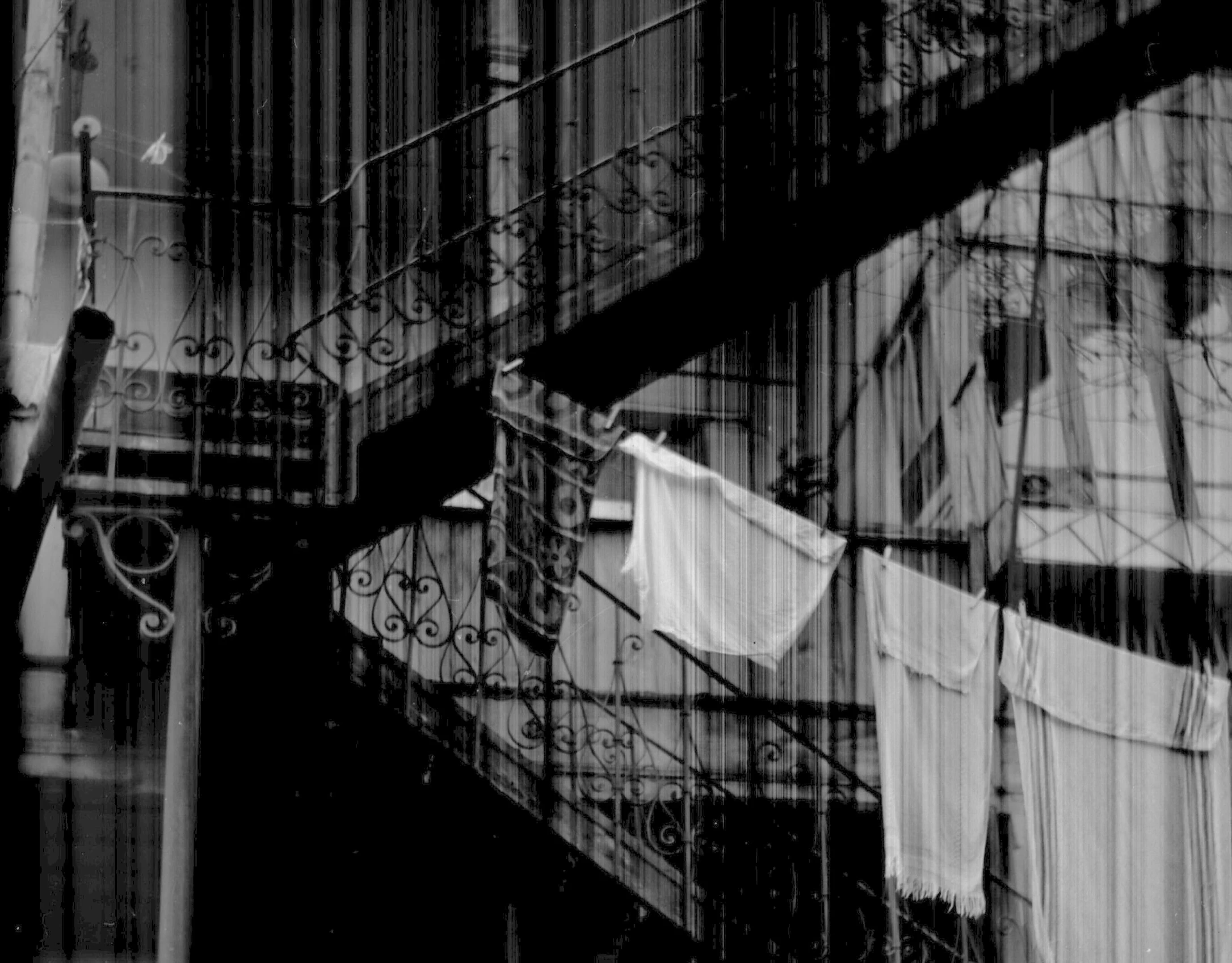 a black and white photo of clothes hanging out to dry, a black and white photo, inspired by André Kertész, baroque, stairways, glass reflections, new orleans, white clothes