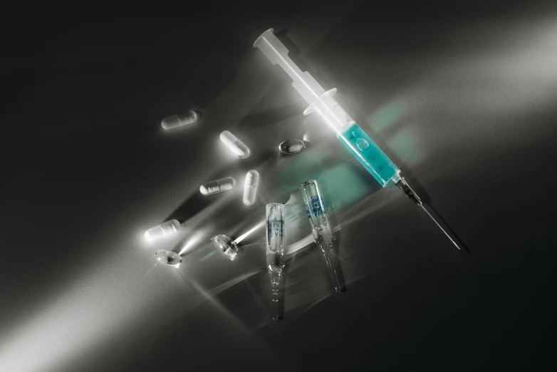 a close up of a syll on a table, syringes, universal volumetric lighting, detailed product image, dark teal lighting
