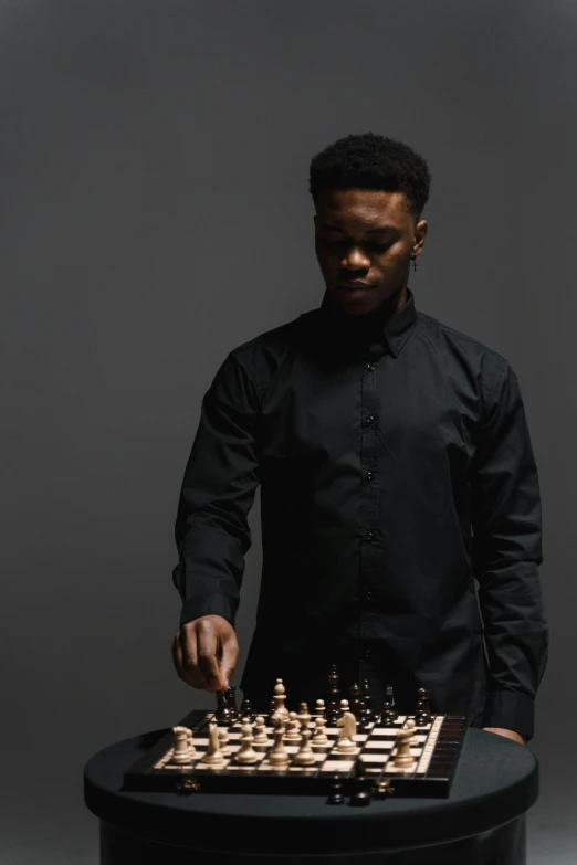 a man in a black shirt playing a game of chess, an album cover, by James Morris, pexels contest winner, ( ( dark skin ) ), confident pose, looking from side, in black uniform