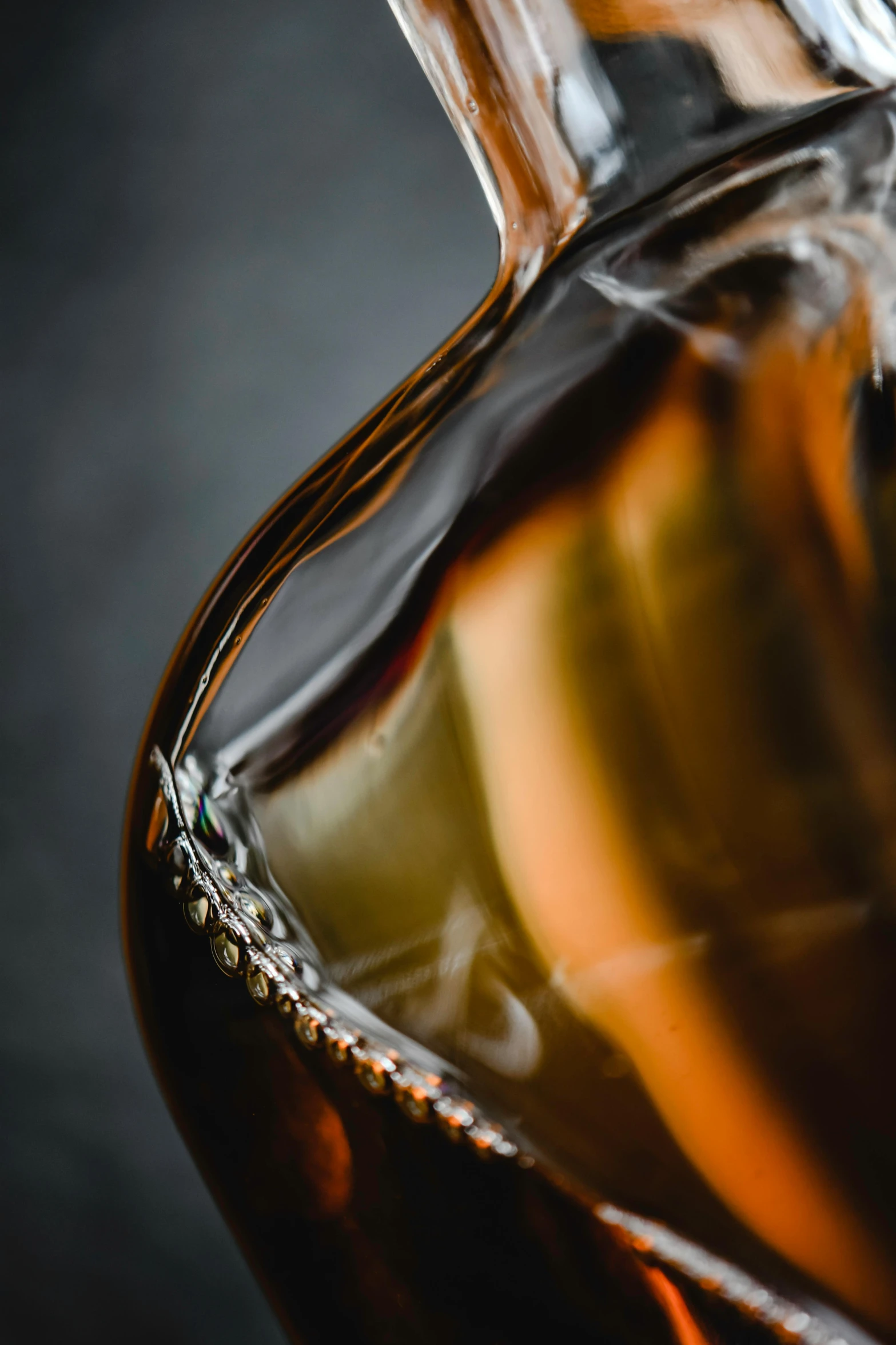 a bottle of whiskey sitting on top of a table, a macro photograph, by David Simpson, curved, caramel, visible stitching, maple syrup sea