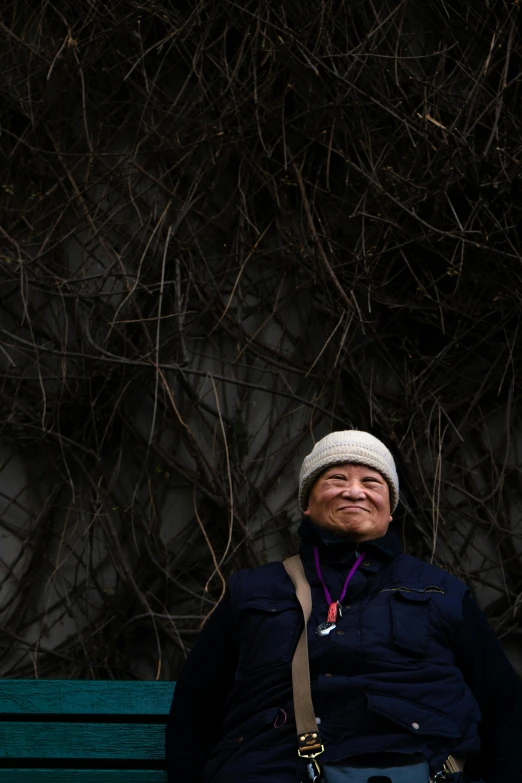 a man sitting on top of a green bench, an album cover, inspired by Chiharu Shiota, unsplash, portrait photo of an old man, made of vines, photographed for reuters, subject is smiling