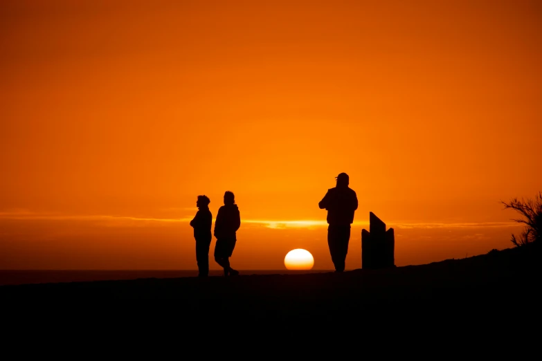 a group of people standing on top of a hill at sunset, by Eglon van der Neer, pexels contest winner, orange glow, the three suns, people's silhouettes close up, high quality photo