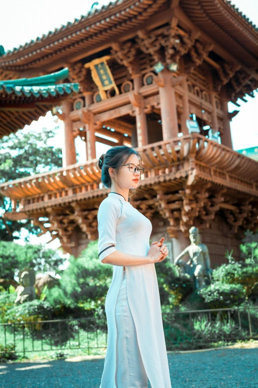 a woman is standing in front of a pagoda, inspired by Cui Bai, pexels contest winner, square, low quality photo, handsome girl, brown