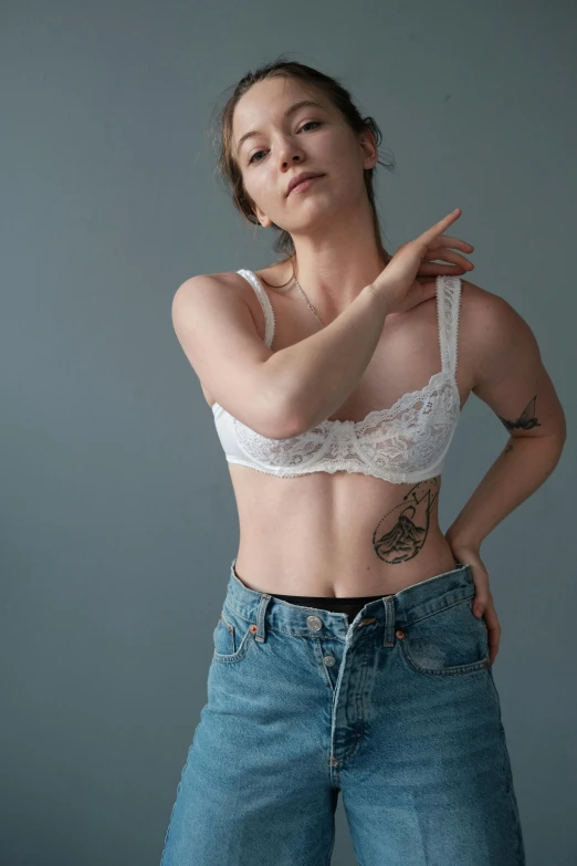 a woman in a white bra top and blue jeans, a tattoo, trending on pexels, nonbinary model, pale skin!, 90's photo, ad image