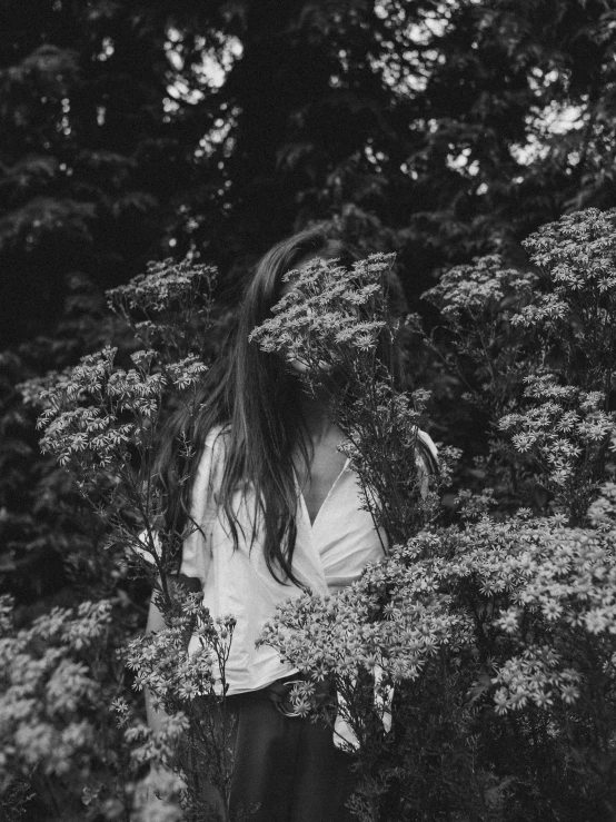 a woman holding a bunch of flowers in front of her face, a black and white photo, by Zofia Stryjenska, unsplash, aestheticism, bushes, girl with long hair, tri - x 4 0 0 tx, (((forest)))