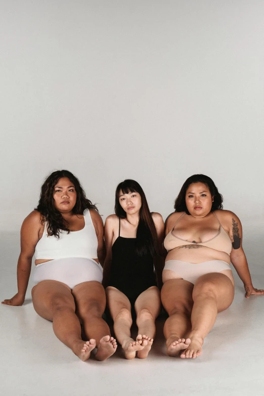 a group of women sitting next to each other, inspired by Vanessa Beecroft, unsplash, her belly is fat and round, half asian, three women, in front of white back drop