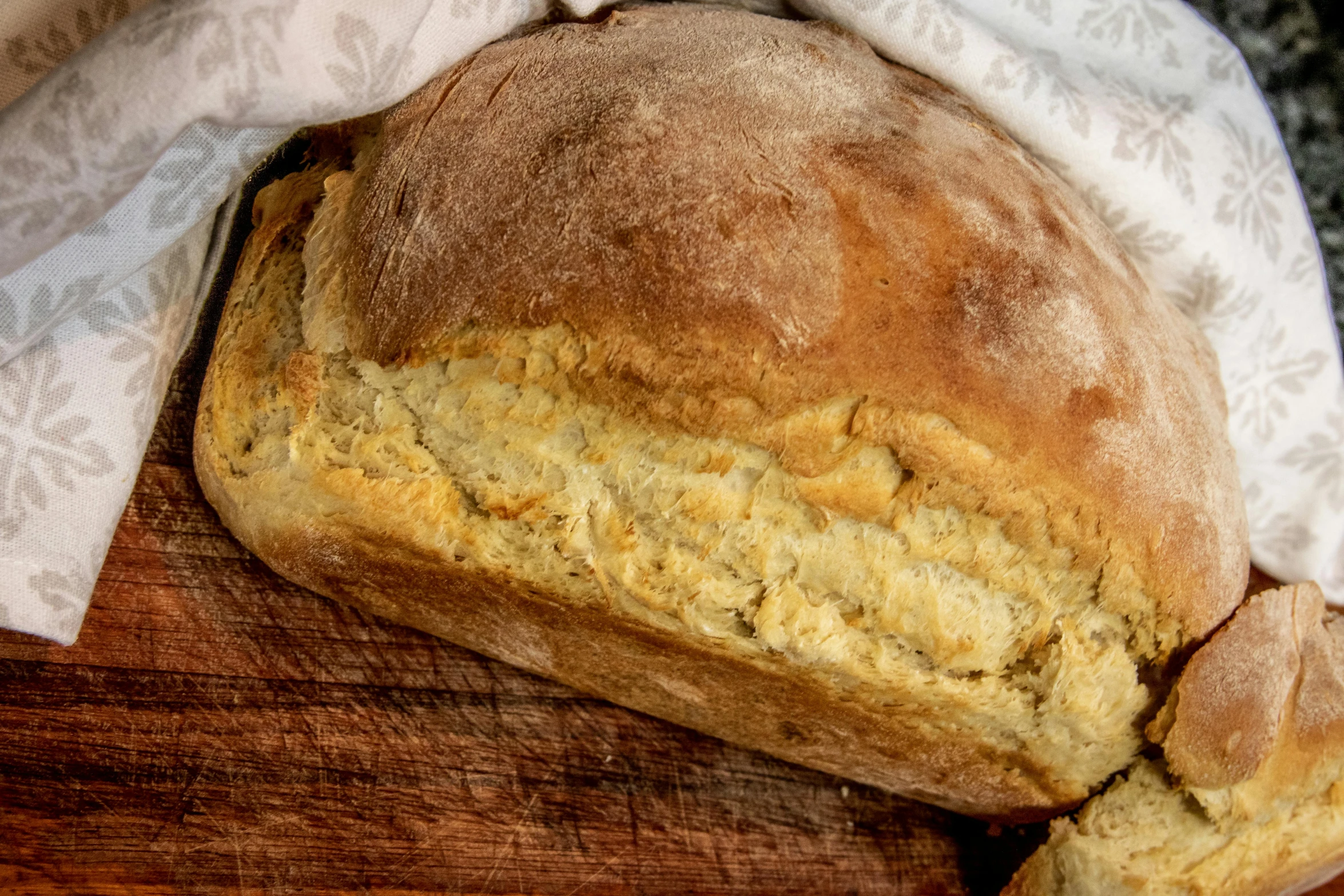 a loaf of bread sitting on top of a wooden cutting board, golden eal, thumbnail, soft and warm, upper body close up