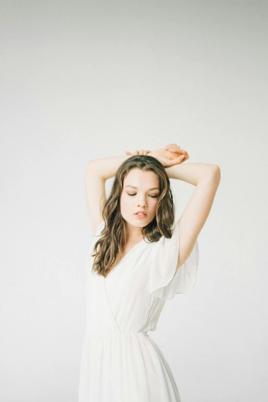 a woman in a white dress posing for a photo, an album cover, unsplash, hailee steinfeld, pale gray skin, hands in her hair. side-view, doing a sassy pose
