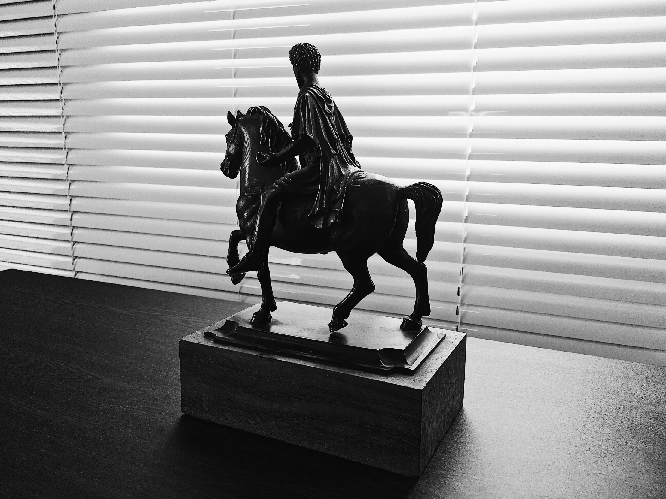 a black and white photo of a statue of a man on a horse, a statue, by Romain brook, unsplash contest winner, fine art, displayed on mahogany desk, view from the side”, ebony art deco, replica model