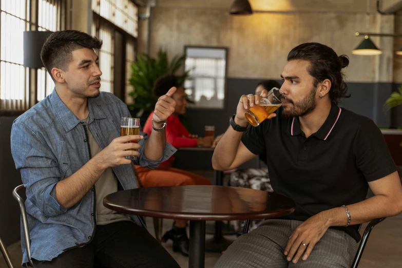 two men sitting at a table drinking beer, by Carey Morris, pexels, charli bowater and artgeem, arguing, aussie baristas, ghutra and egal