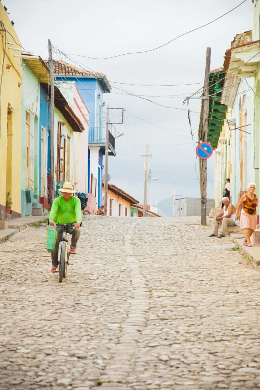 a person riding a bike down a cobblestone street, cuba, slide show, multicoloured, square