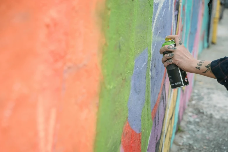 a person spray painting on a colorful wall, molotow premium color palette, hard edges! graffiti, pastell colours, multi - coloured