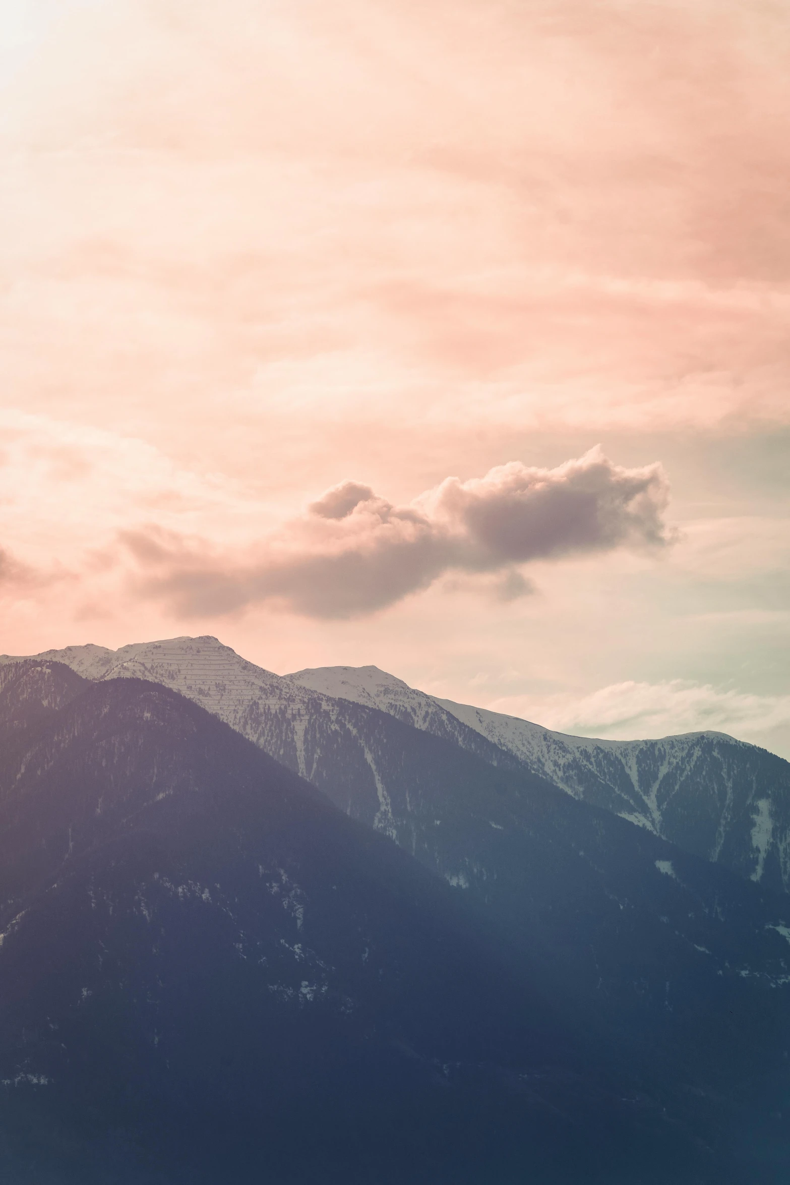 a person standing on top of a snow covered mountain, by Tobias Stimmer, trending on unsplash, romanticism, light pink clouds, “ aerial view of a mountain, late summer evening, sunfaded