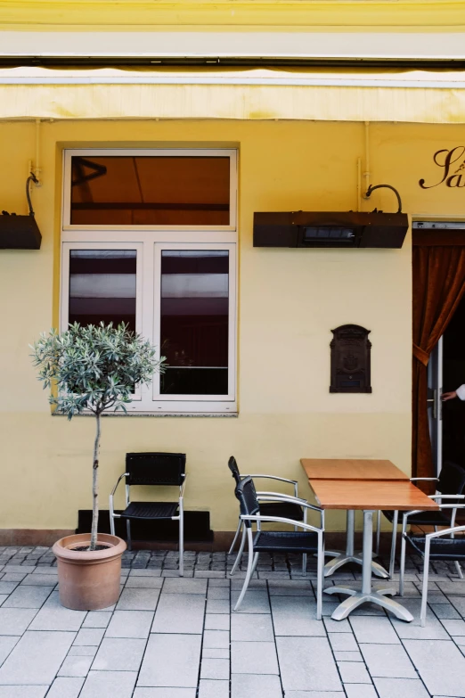 a person sitting at a table outside of a restaurant, inspired by Jan Kupecký, pale yellow walls, karo, panorama, awnings