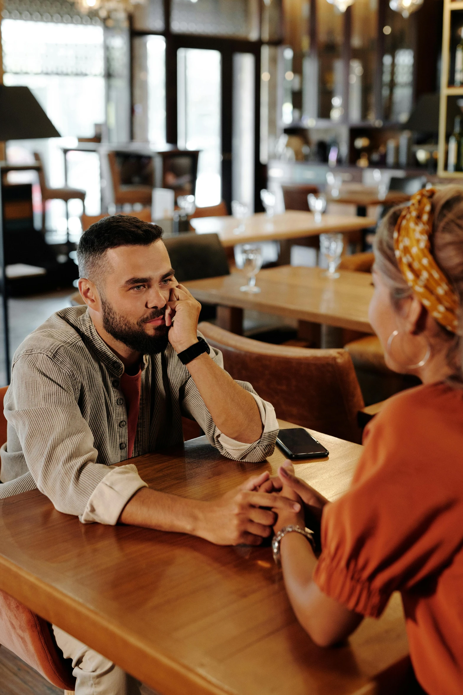 a man and woman sitting at a table in a restaurant, trending on pexels, emotional conflict, lgbtq, pondering, religious