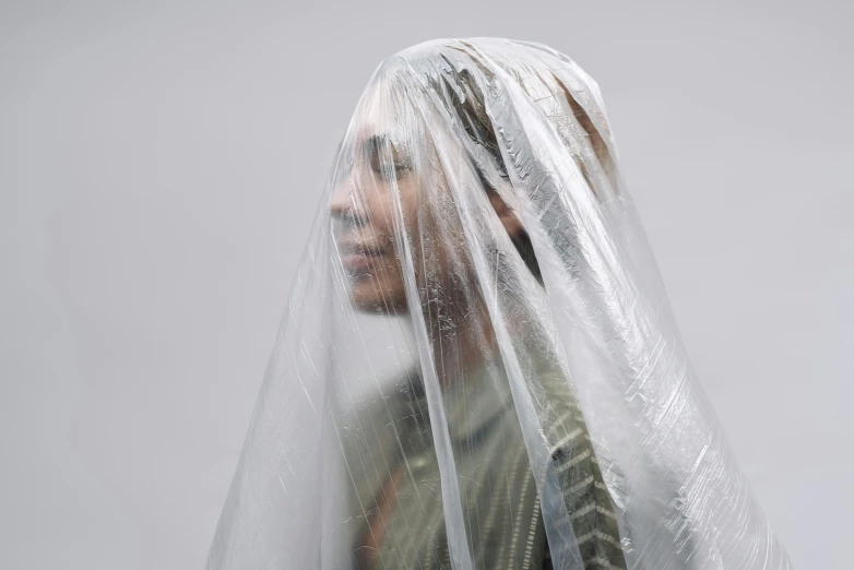 a close up of a person wearing a veil, an album cover, inspired by Anna Füssli, trending on unsplash, hyperrealism, wearing a plastic garbage bag, on a gray background, hammershøi, wet hair