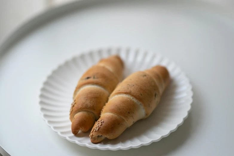 two croissants on a paper plate on a table, unsplash, mingei, kek, taiwan, decorative, sausage