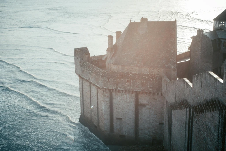a castle sitting on top of a cliff next to the ocean, wall of water either side, contre jour, arial shot, imogen poots d&d paladin