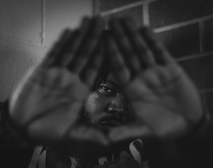 a man making a stop sign with his hands, a black and white photo, by Adam Chmielowski, unsplash, graffiti, donald glover, symmetry!! portrait of akuma, black hands with black claws, black jesus