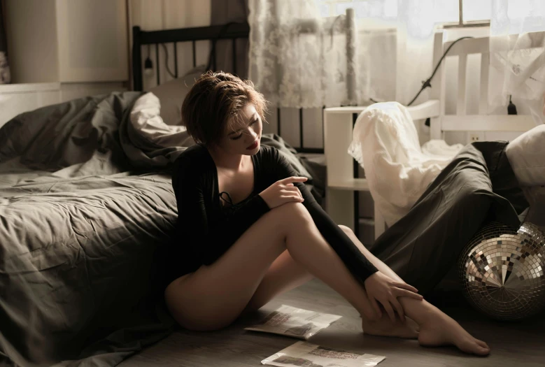 a woman sitting on the floor next to a bed, a portrait, unsplash contest winner, romanticism, various lacivious seducing poses, handsome girl, uncropped, very thin
