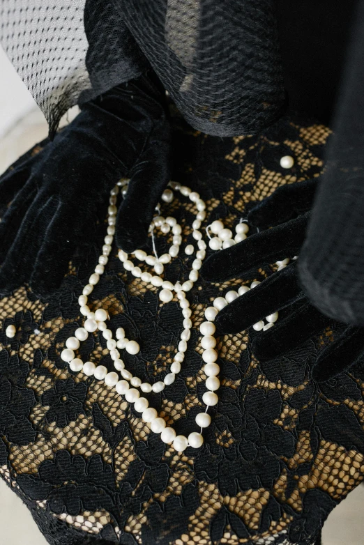 a close up of a purse with pearls on it, wearing black old dress and hat, detailed product shot, dressed in a frilly ((lace)), detailed jewellery