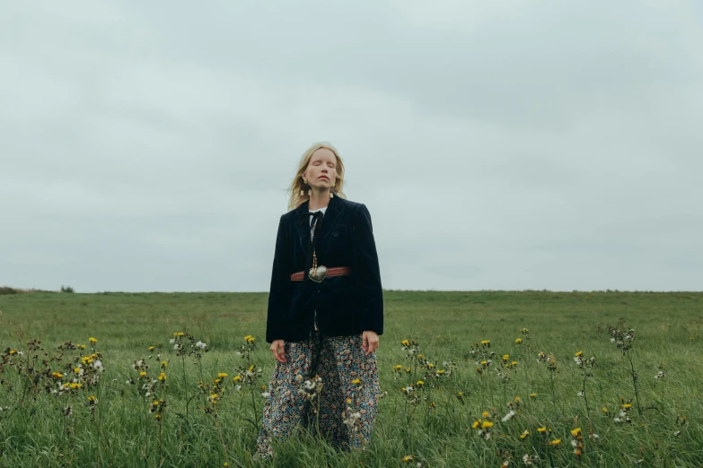 a woman standing in a field of tall grass, an album cover, inspired by Derek Jarman, unsplash, renaissance, older woman, seaside, liz truss, standing in a field with flowers