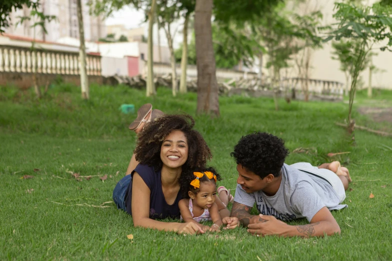 a man and woman laying in the grass with a baby, by Samuel Silva, pexels contest winner, with afro, in sao paulo, avatar image, cute woman