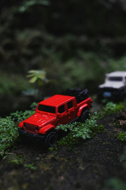 a red toy truck sitting on top of a lush green forest, unsplash, photorealism, jeep wrangler, micro machines, rain lit, crawling