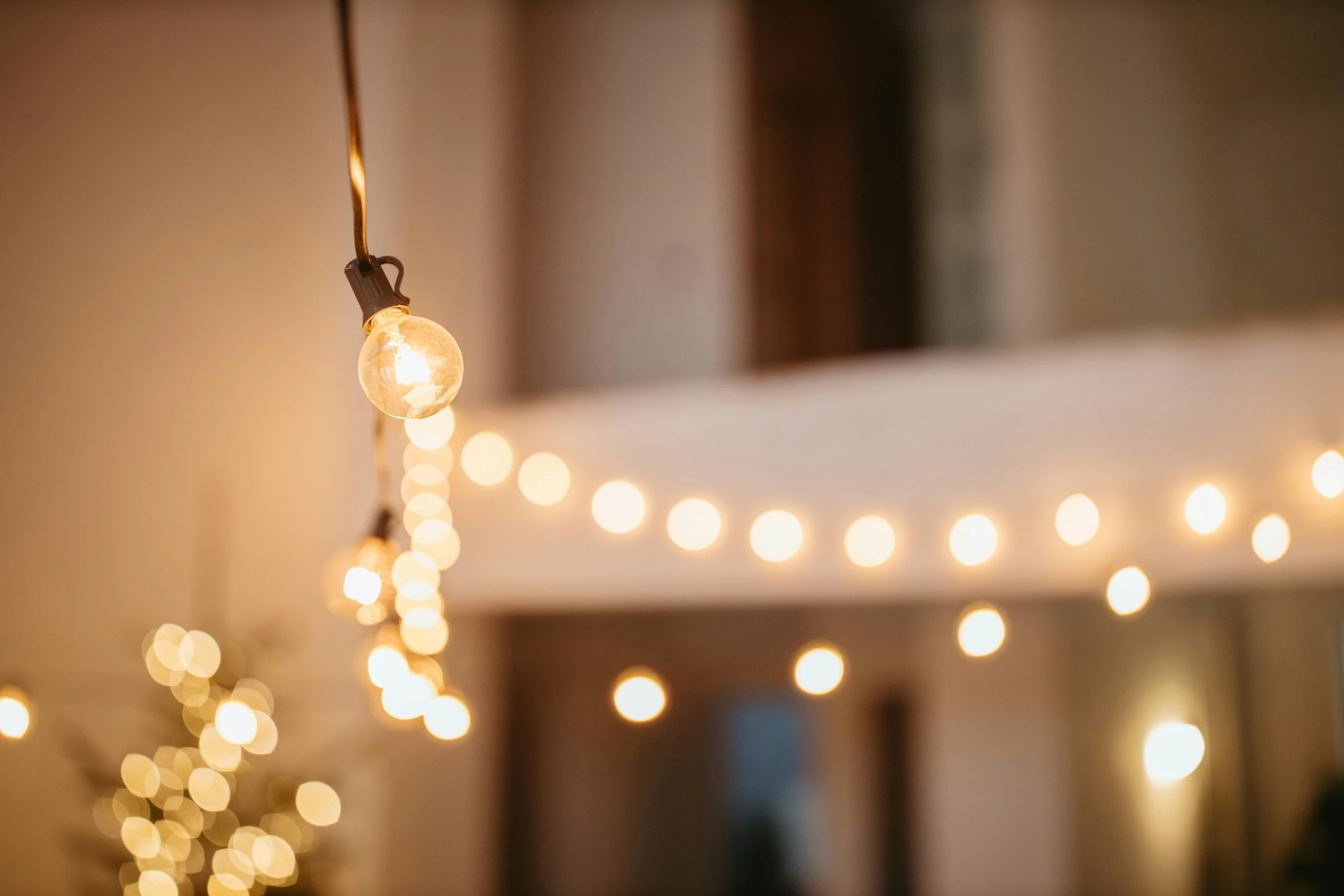 a string of lights hanging from a ceiling, by Helen Stevenson, unsplash, light and space, soft filtered outdoor lighting, close up shot from the side, entertaining, rustic