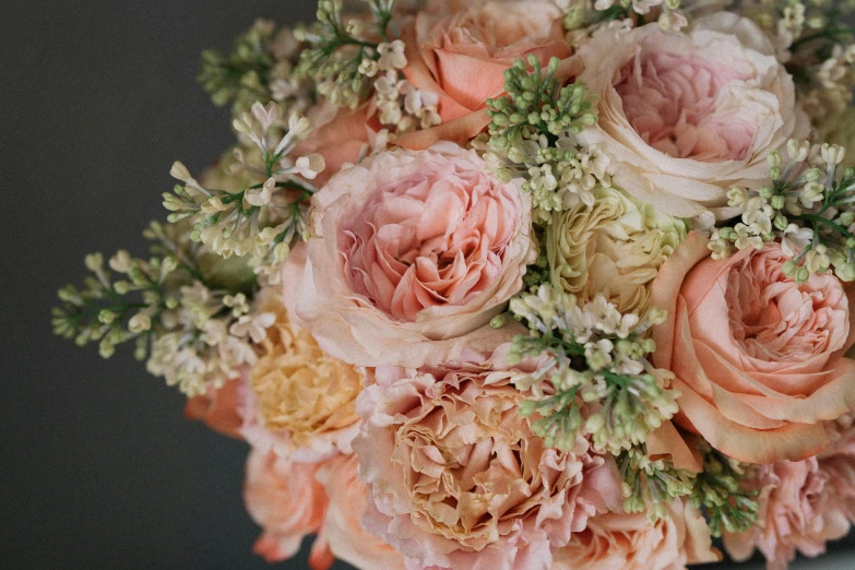a close up of a bouquet of flowers on a table, in shades of peach, on black background, subtle detailing, award - winning details