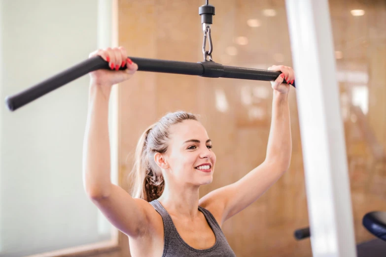 a woman using a pull up bar in a gym, by Emma Andijewska, private press, looking happy, manuka, no cropping, very sunny