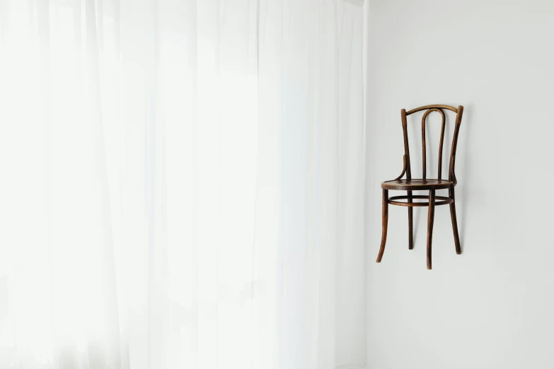 a wooden chair sitting in front of a window, inspired by Méret Oppenheim, pexels contest winner, postminimalism, in front of white back drop, hanging from white web, antique style, made of bronze