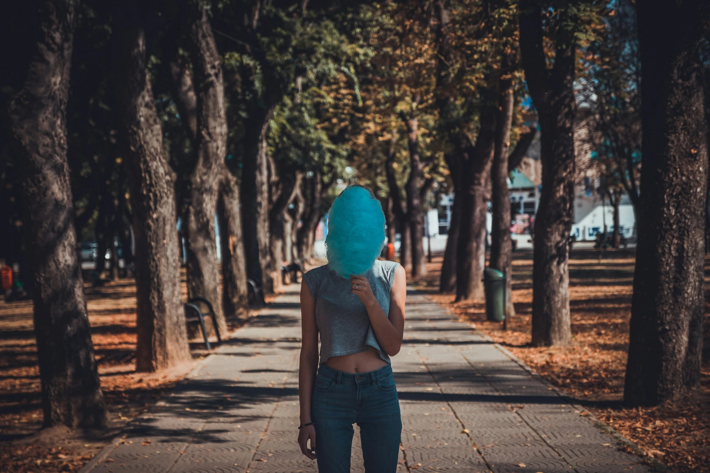 a woman walking down a sidewalk with a blue head covering her face, pexels contest winner, hair made of trees, sunfaded, a park, girls