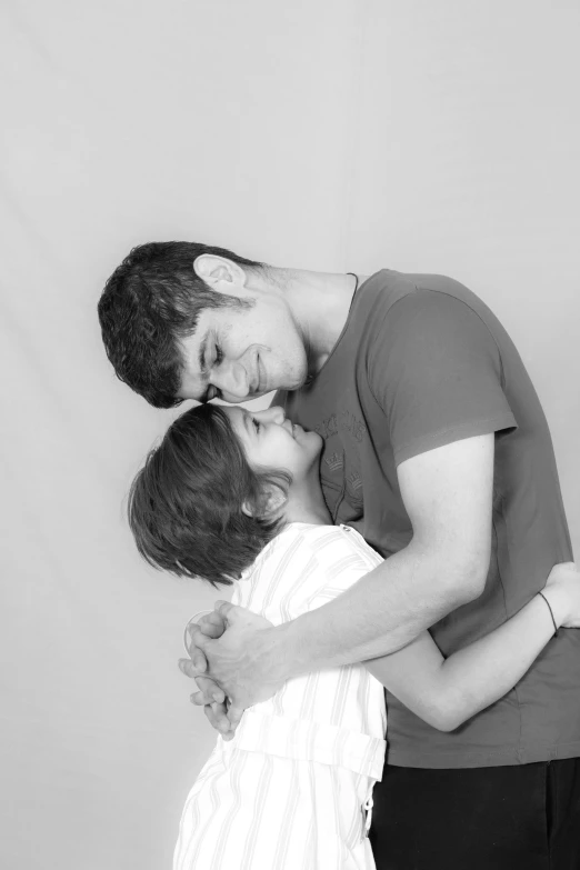 a black and white photo of a man kissing a little girl, a black and white photo, flickr, bradley james and colin morgan, in a photo studio, hugging each other, farid ghanbari