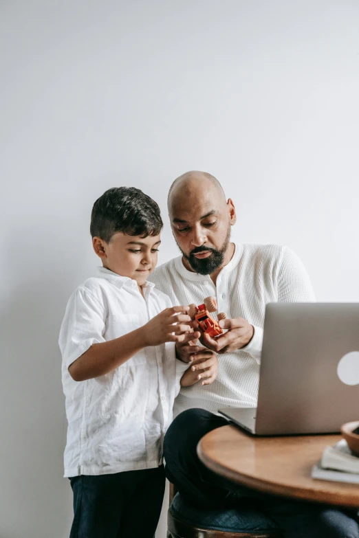 a man and a boy looking at a laptop, pexels contest winner, hearts, one holds apple in hand, ismail, d&d boss