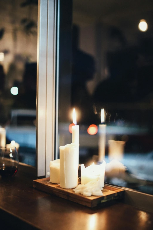 a couple of candles sitting on top of a window sill, trending on unsplash, romanticism, cozy cafe background, multiple stories, standing still, softly lit