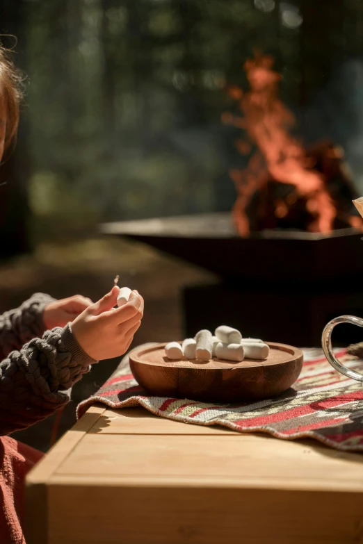 a little girl sitting at a table with marshmallows, a digital rendering, pexels contest winner, weta workshop the hobbit, campfire, detail shot, environmental shot