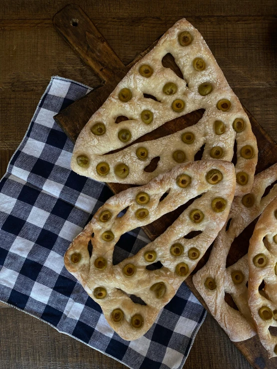 a table topped with slices of pizza covered in olives, inspired by Géza Dósa, art nouveau, triangular face, bakery, lattice, 1940s food photography