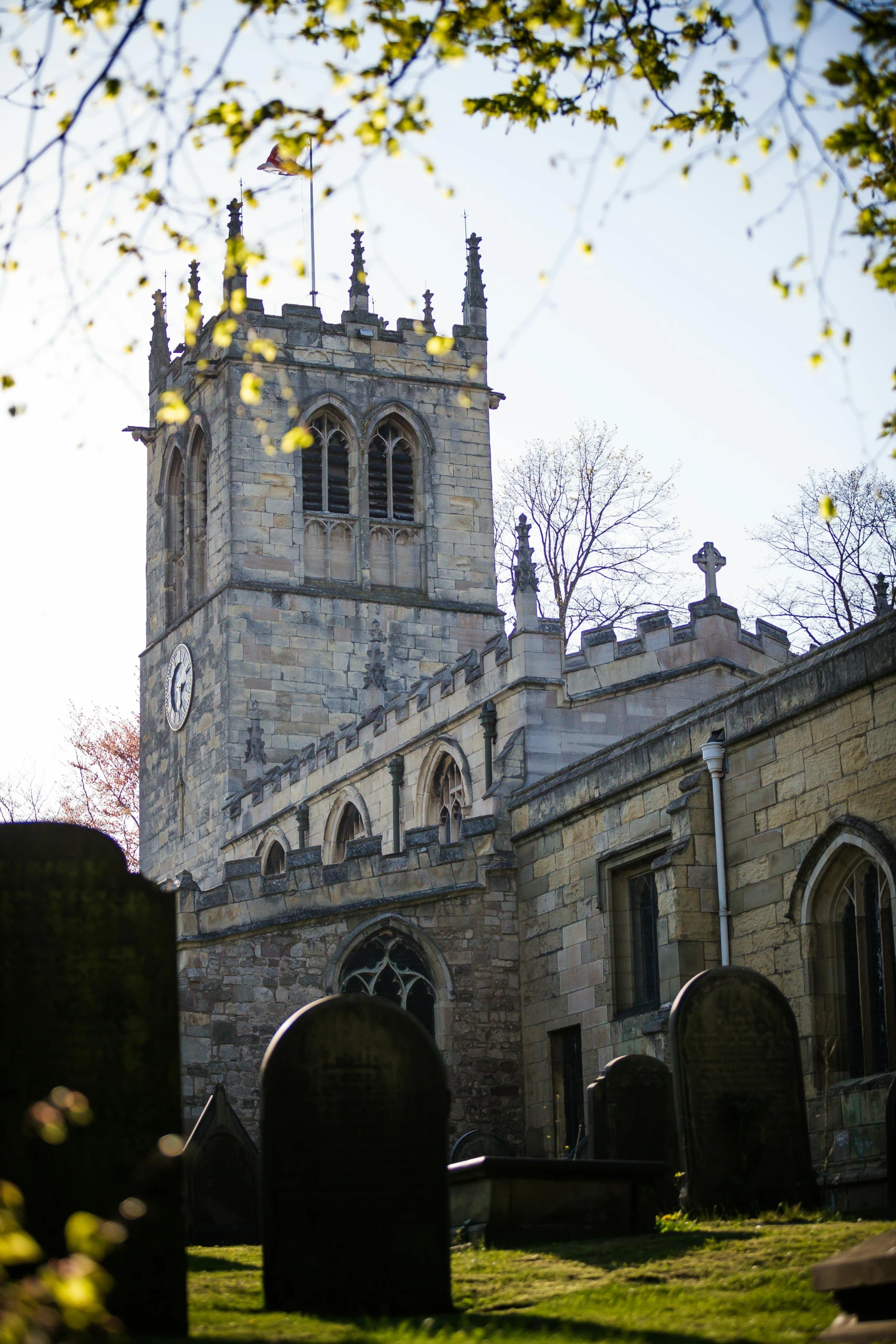 a cemetery with a clock tower in the background, by Kev Walker, romanesque, shot from low angle, churches, yorkshire, square