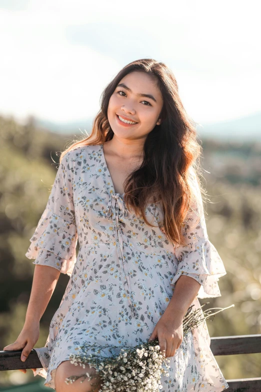 a woman standing in front of a fence, by Robbie Trevino, dressed in a flower dress, smiling young woman, standing in front of a mountain, white background