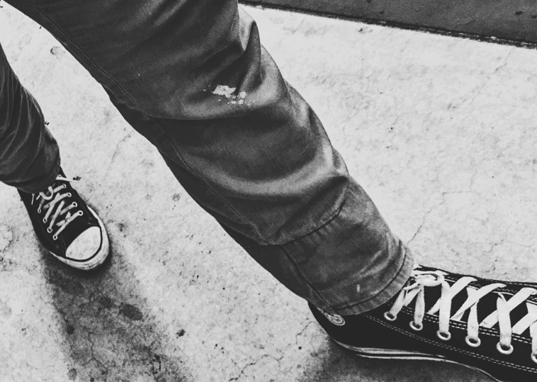 a black and white photo of a pair of sneakers, a black and white photo, pexels, realism, worn pants, punk rock, stalking, photo on iphone