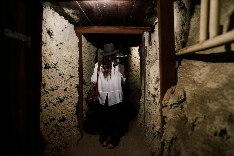 a woman in a white shirt and hat walking through a tunnel, happening, inside a haunted house, bunkers, profile image