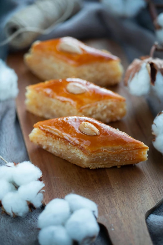 a wooden cutting board topped with pastries and cotton, inspired by Nadim Karam, hurufiyya, caramel, low detail, caparisons, square