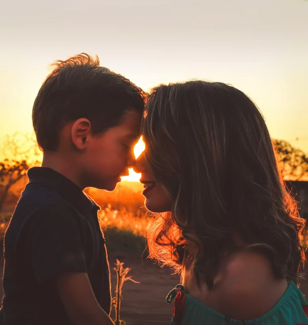 a couple of kids standing next to each other, pexels contest winner, sunset glow around head, profile pic, maternal, in love