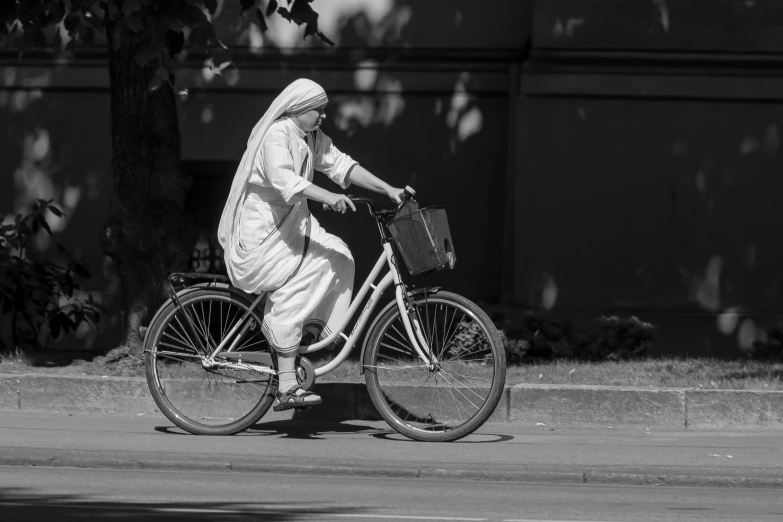 a black and white photo of a woman riding a bike, figuration libre, dressed in white robes, helsinki, india, nun outfit