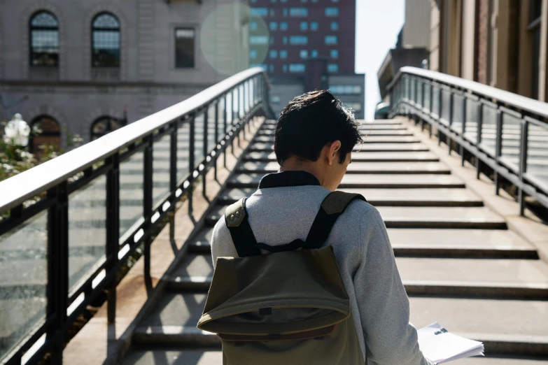 a man with a backpack walking down a set of stairs, inspired by Vivian Maier, unsplash, academic art, square backpack, asian male, seen from the back, studying