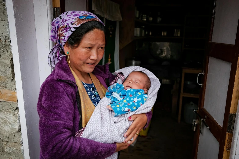 a woman holding a baby in her arms, pexels contest winner, cloisonnism, square, taken with sony alpha 9, in a village, at home